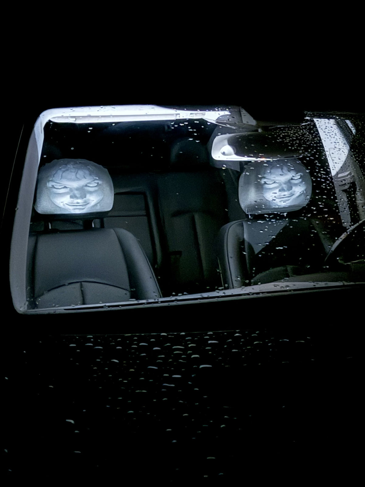 Ghost faces visible through the windshield from outside the car