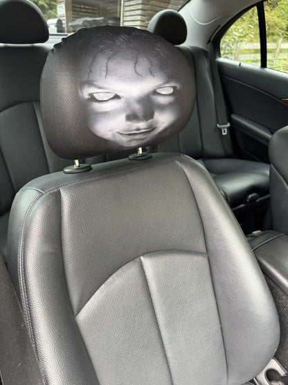 Ghost headrest cover visible through the side window of a parked car