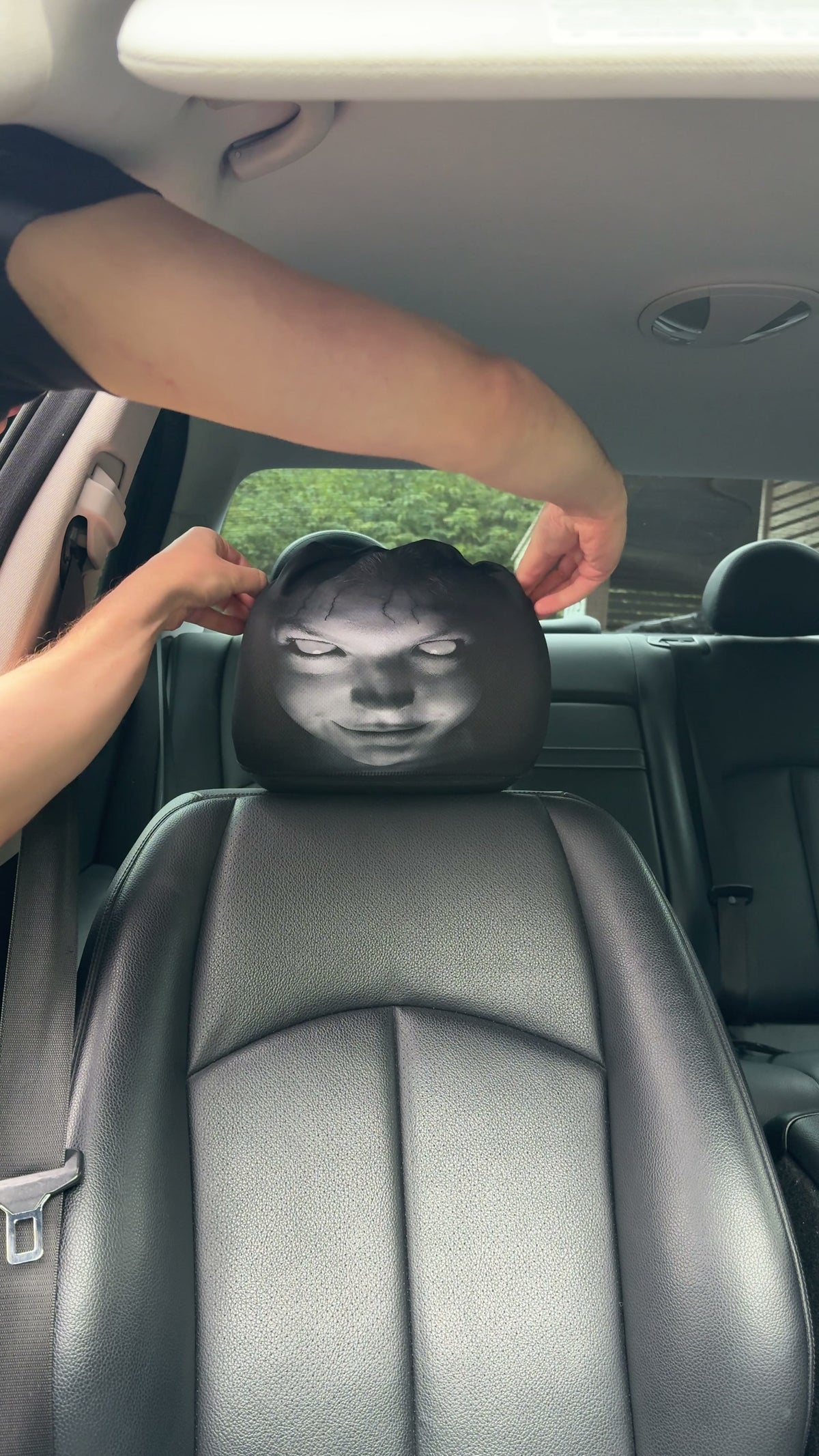 Hands pulling the PhantomSeat cover over a car headrest